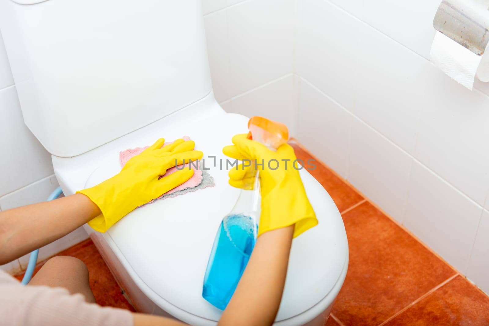Woman cleaning toilet seat using liquid spray and pink cloth wipe restroom at house, female wearing yellow rubber gloves she sitting and wash cleaner bowl bathroom wc, Housekeeper healthcare concept