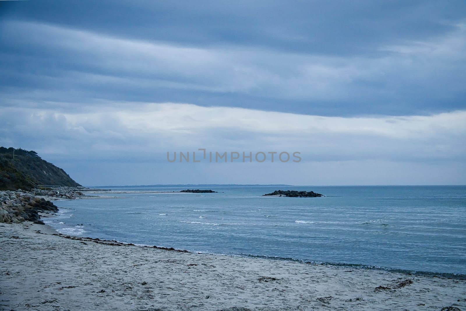 Hundested, Denmark on the cliff overlooking the sea. Baltic Sea coast, grassy meadow, beach. Clouds on horizon. Landscape photo from Scandinavia.