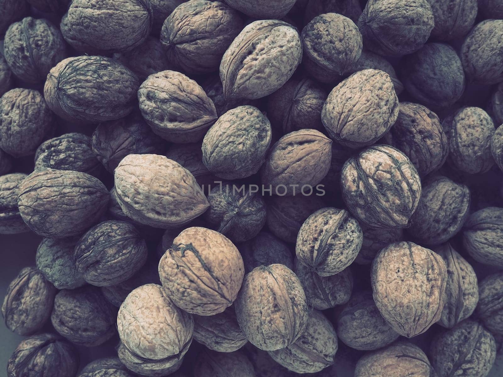 Lots of walnuts close up. Unpeeled walnuts with shells. A bunch of nuts. background. Vegetarian healthy diet. Polyunsaturated fatty acids, omega 3.