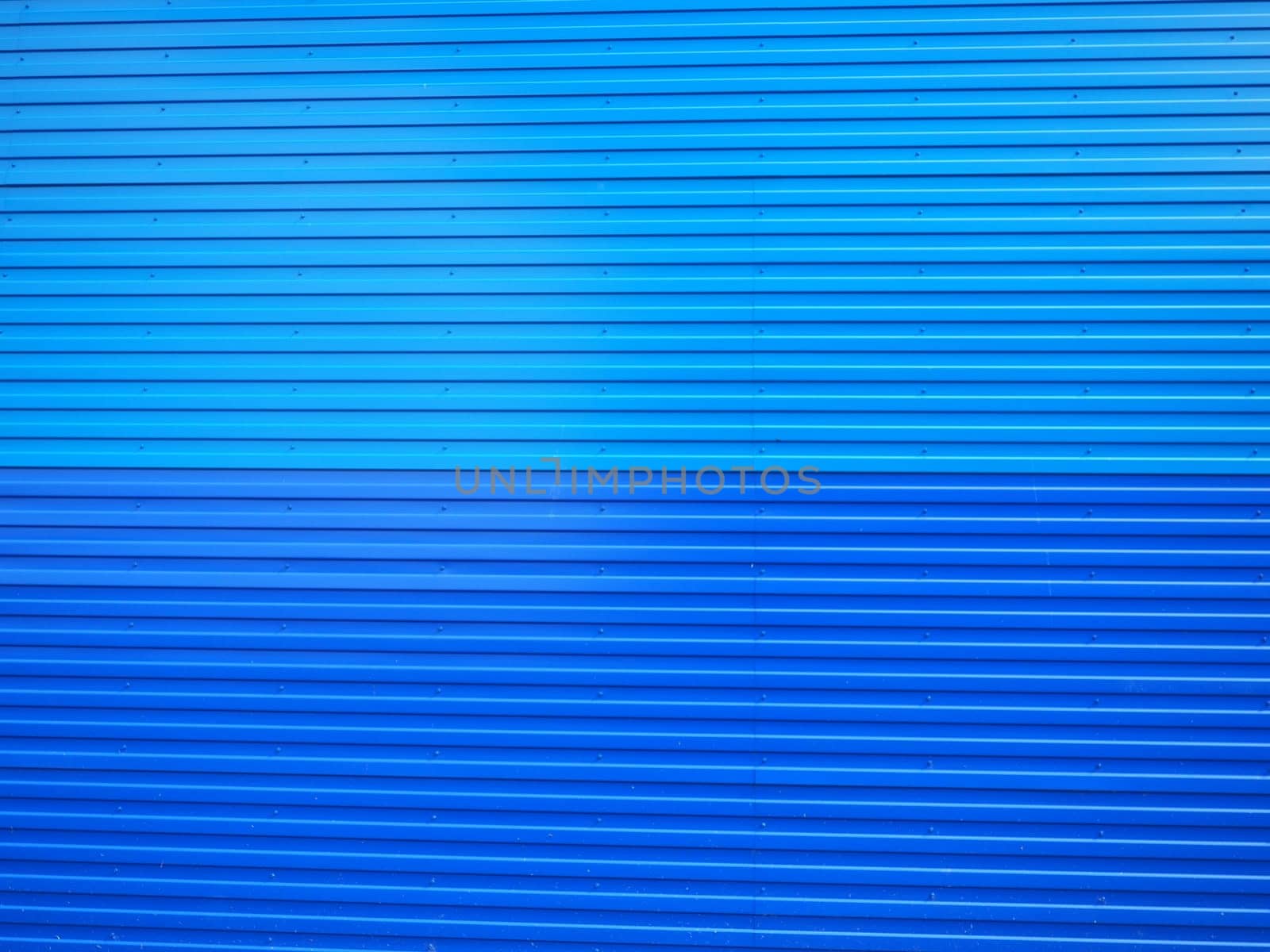 Profiled sheet. Facing wall or roofing building material used in construction in the construction of external fences, walls and roofs. Corrugated blue metal background with gradient.