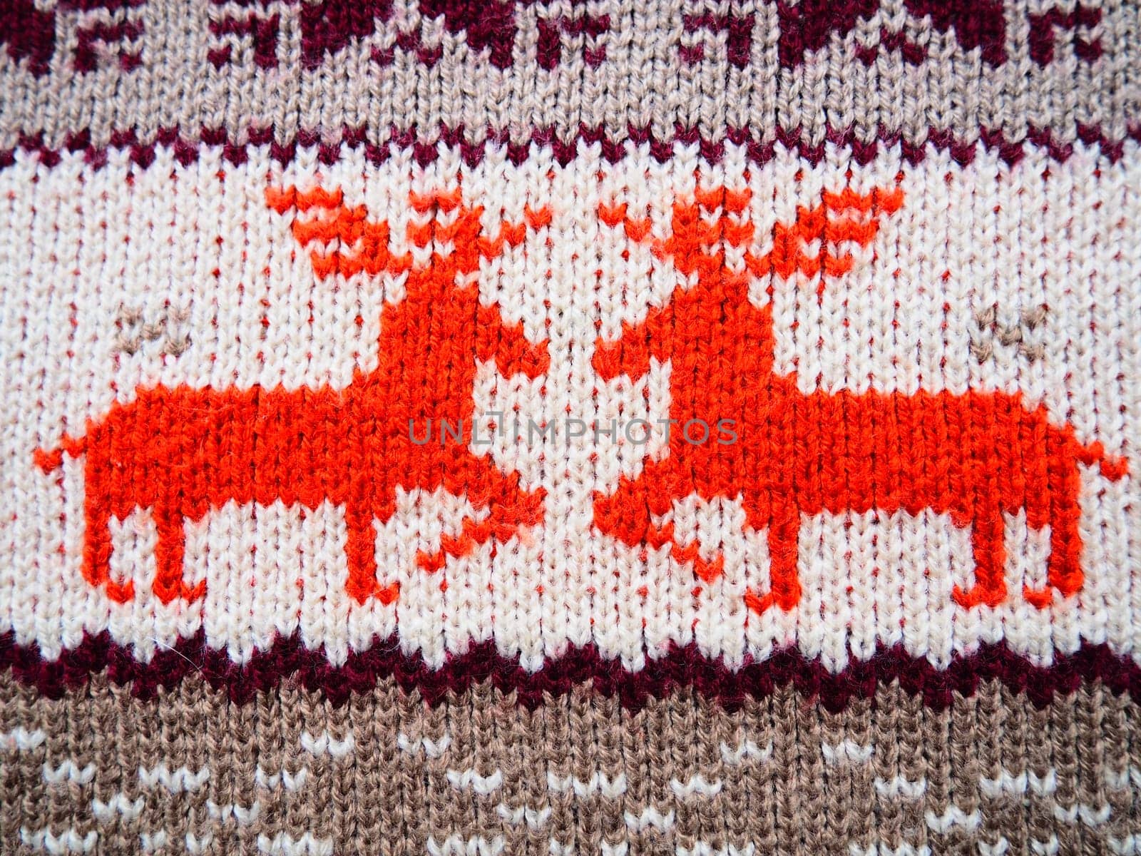 Jacquard knitted pattern. Geometric ornament for Christmas or New Year. Two red deer on a white knitted background with horizontal zigzags. Winter fashionable modern animal traditional folk ornament