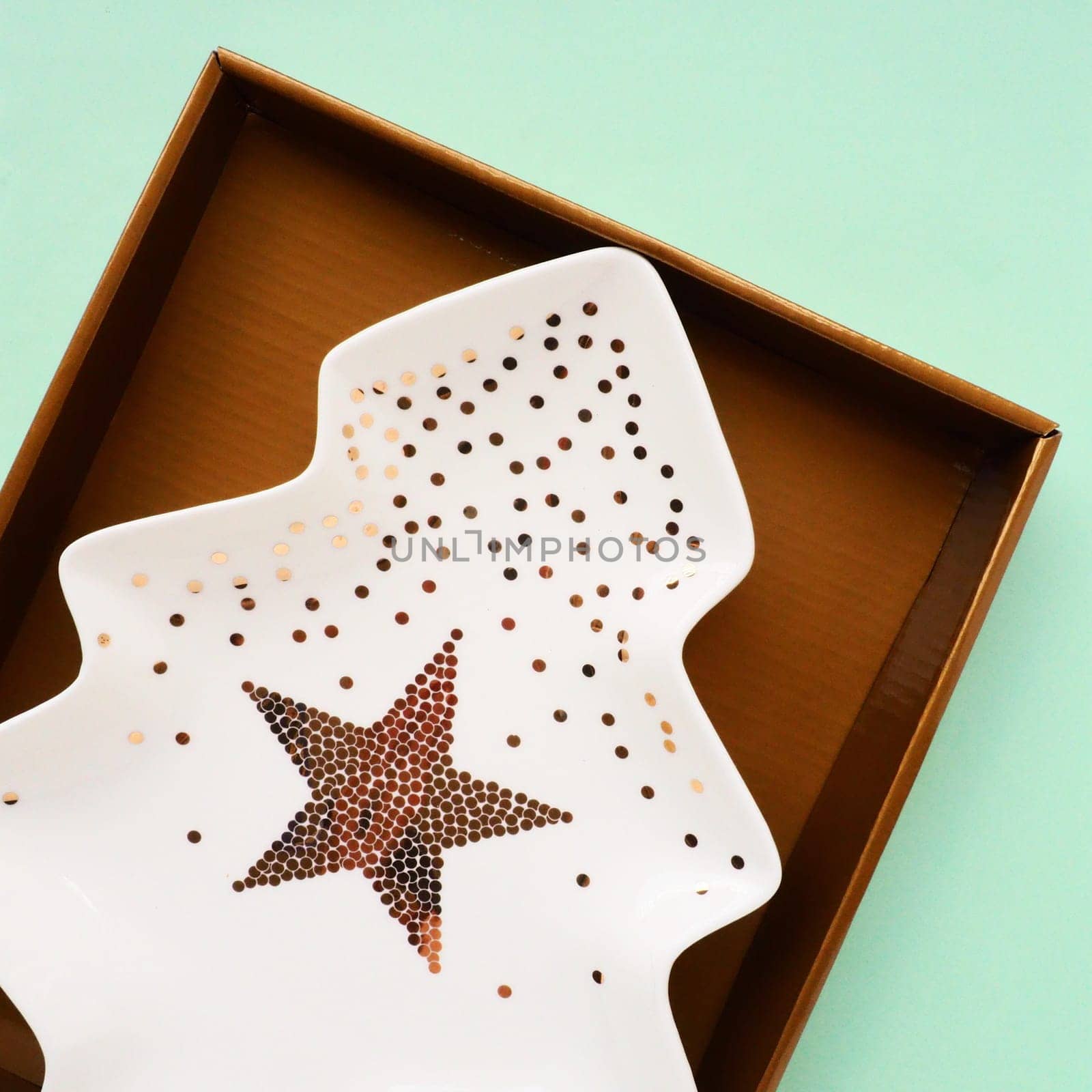 A plate in the shape of a Christmas tree with gold ornaments and a star in the middle. Gift wrapping. Green background. New Year Christmas card. Background for advertising and lettering. Copy space