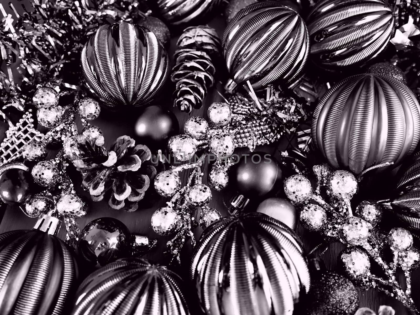 Christmas background with Christmas decorations, holiday balls, bells, bows, fir cone, Christmas tinsel. Happy New Year and Merry Christmas. Black and white monochrome photo with lilac filter