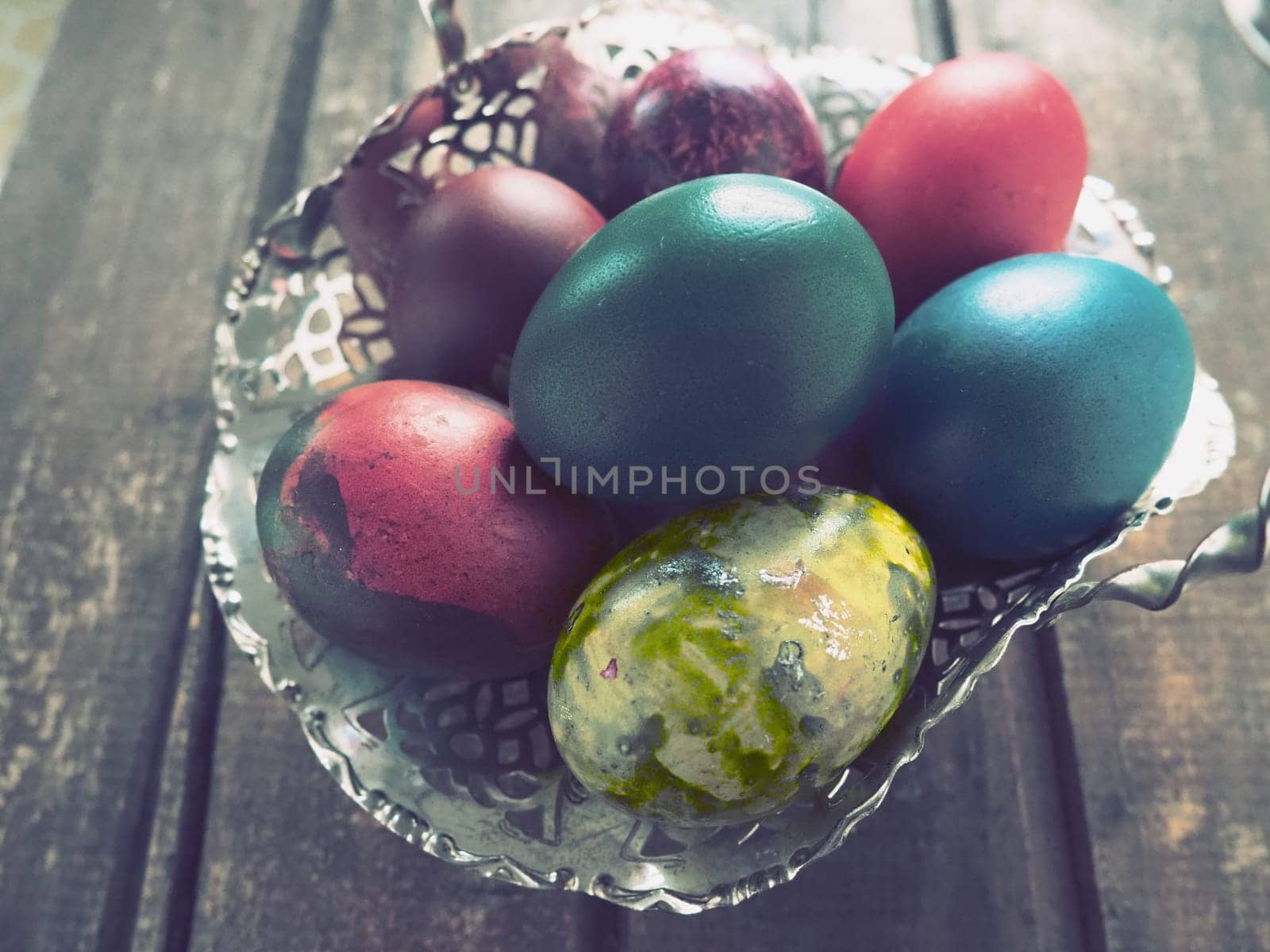 Easter colored eggs in an old metal candy bowl on a wooden table. Easter, the Resurrection of Christ, the Bright Resurrection of Christ, the most ancient and Christian holiday.