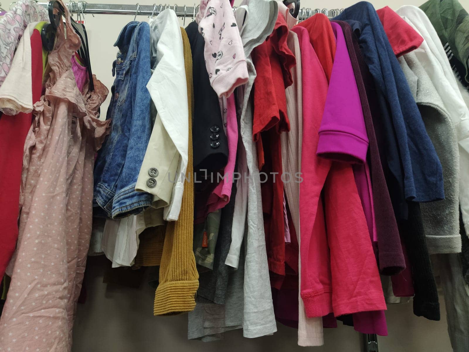 Clothes hung on hangers. Assortment of second hand store. Children's and women's shirts, blouses, sweaters hanging on a rack, ready for sale to customers. Saving money. Belgrade Serbia 22 April 2022