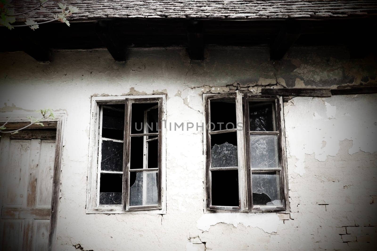 Abandoned spooky old house. Wooden windows and doors. The hut is a mud hut. Samani house. White stucco plaster. Halloween theme. Aging, loneliness, departure, war and devastation. Ukraine, Donbass.