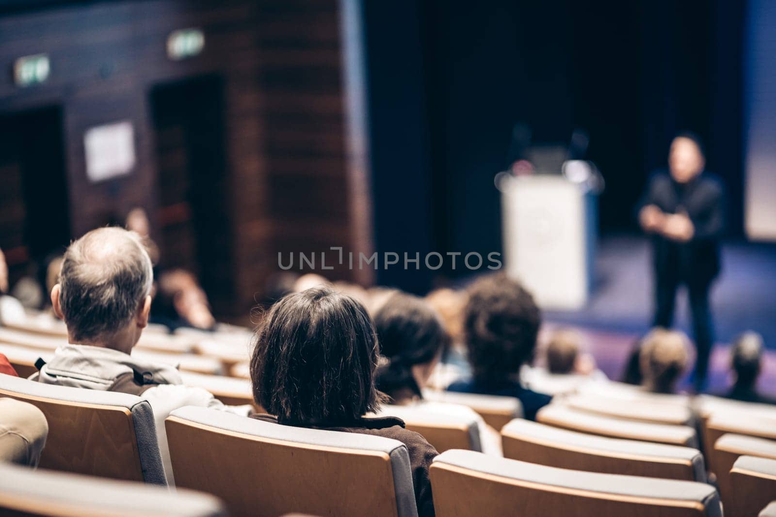 Speaker giving a talk in conference hall at business event. Rear view of unrecognizable people in audience at the conference hall. Business and entrepreneurship concept