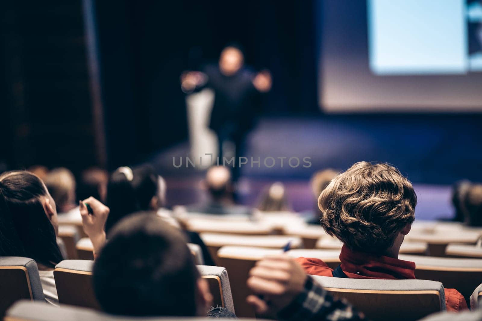 Speaker giving a talk in conference hall at business event. Rear view of unrecognizable people in audience at the conference hall. Business and entrepreneurship concept