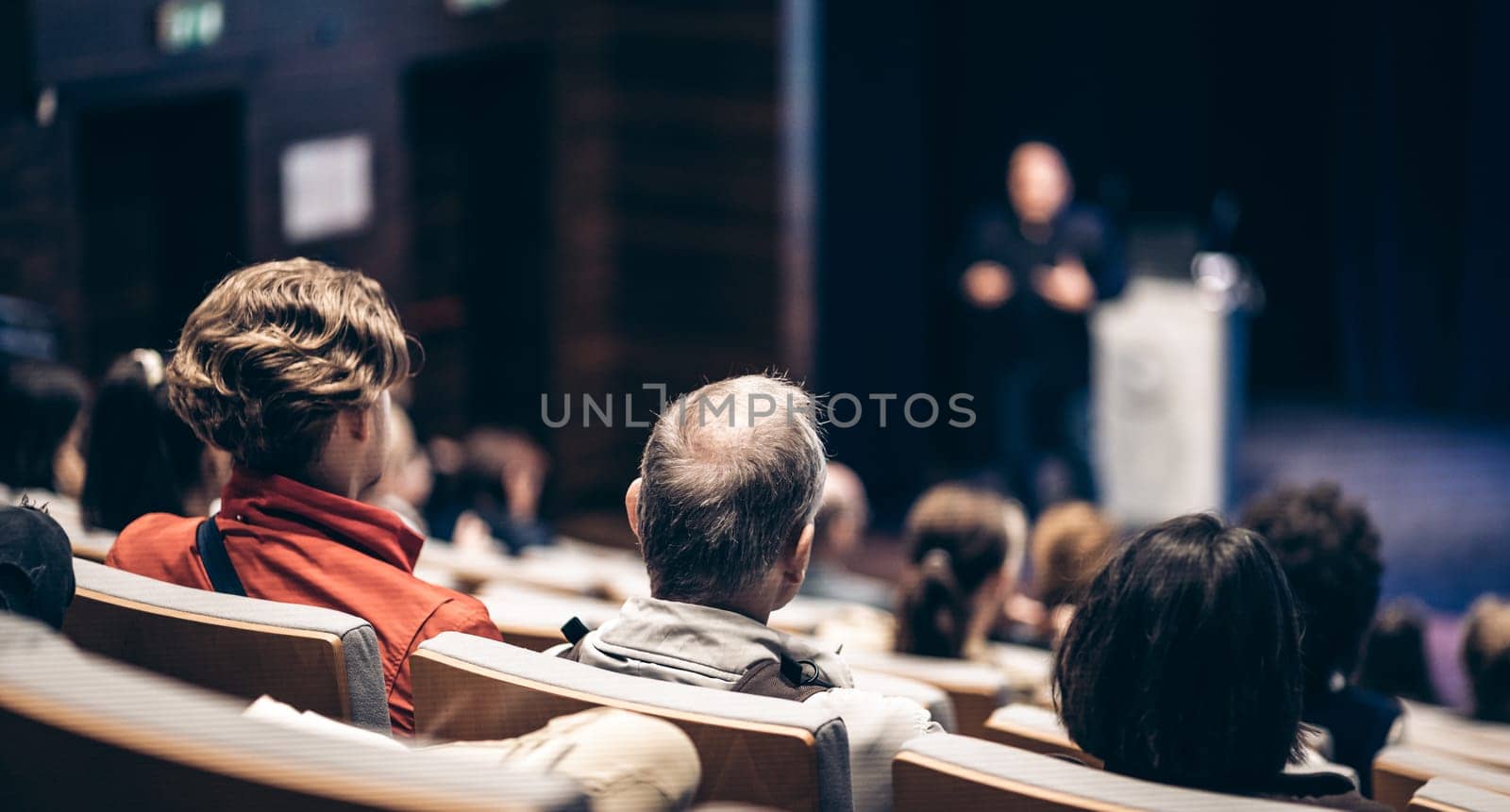 Speaker giving a talk in conference hall at business event. Rear view of unrecognizable people in audience at the conference hall. Business and entrepreneurship concept