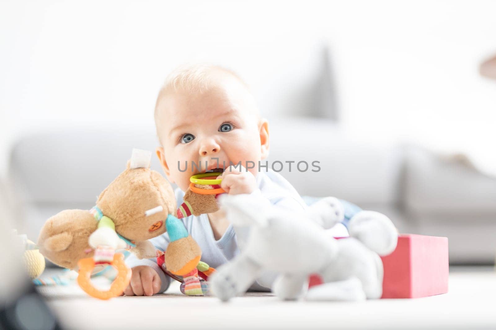Cute baby boy playing with toys on mat at home Baby activity and play center for early infant development. Baby playing at home