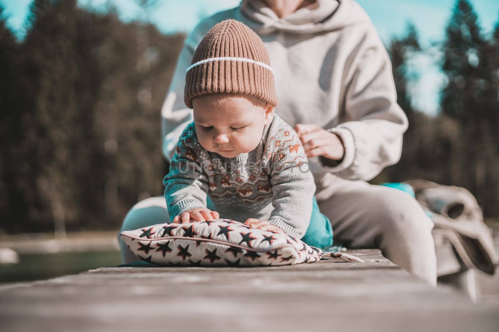Happy family. Young mother playing with her baby boy infant oudoors on sunny autumn day. Portrait of mom and little son on wooden platform by lake. Positive human emotions, feelings, joy