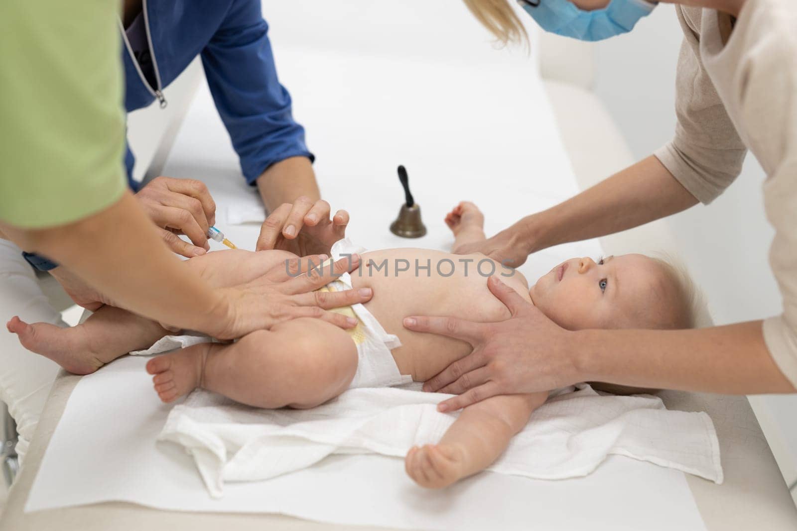 Baby beeing vaccinated by pediatrician in presence of his mother. Preventive vaccination against Diphtheria, whooping cough, tetanus, hepatitis, haemophilus influenzae, pneumococcus, poliomyelitis.