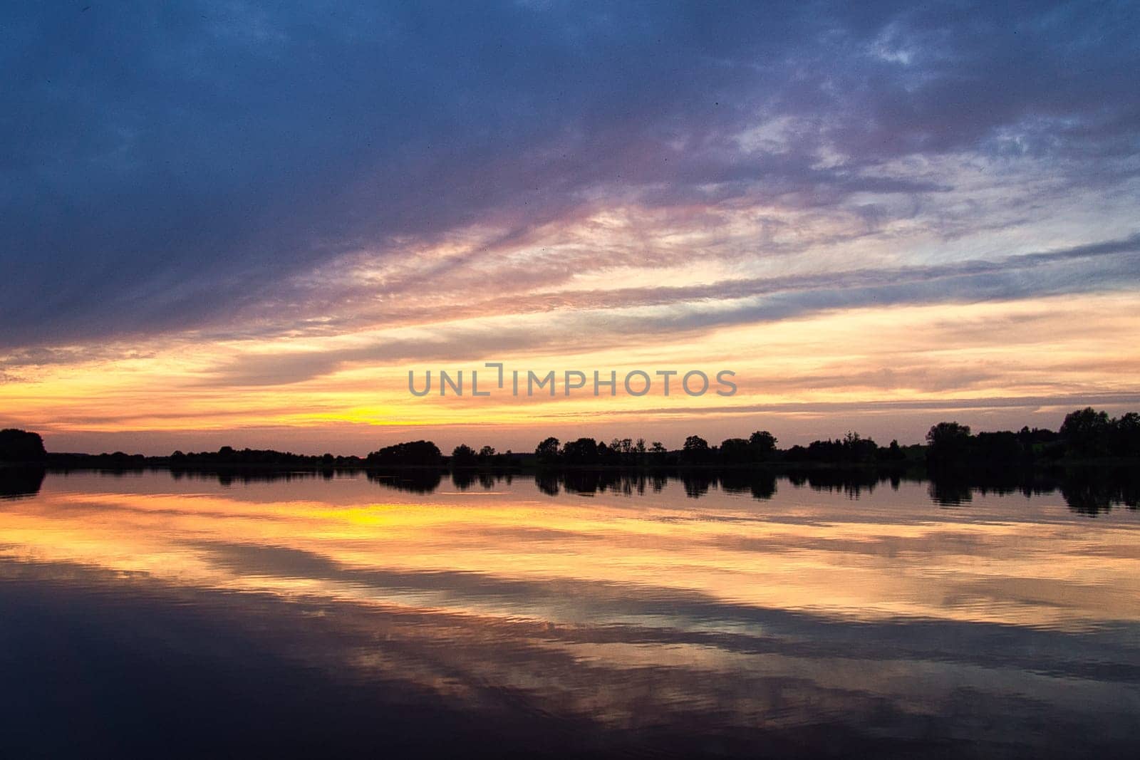 reflection of the sky in the water. gold, yellow and pink colors of the sky are reflected in the lake. Tranquility that makes you dream. Relaxation that a vacation can bring