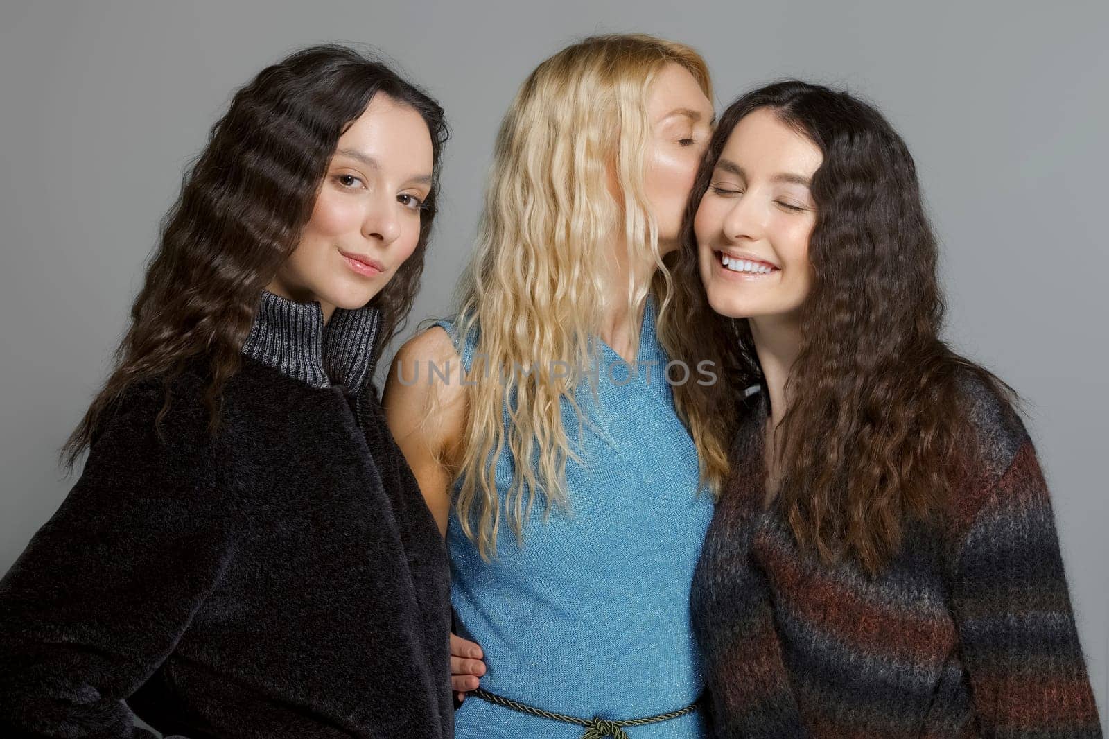 Three attractive girls in woolen coats posing in studio. Gossip girls.