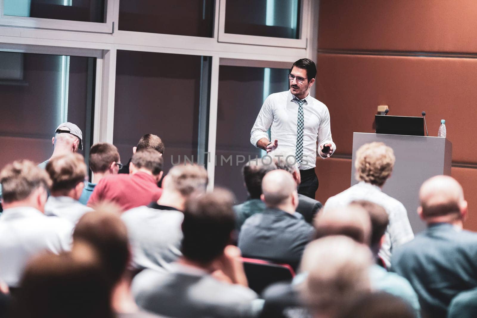 Speaker giving a talk in conference hall at business event. Audience at the conference hall. Business and Entrepreneurship.
