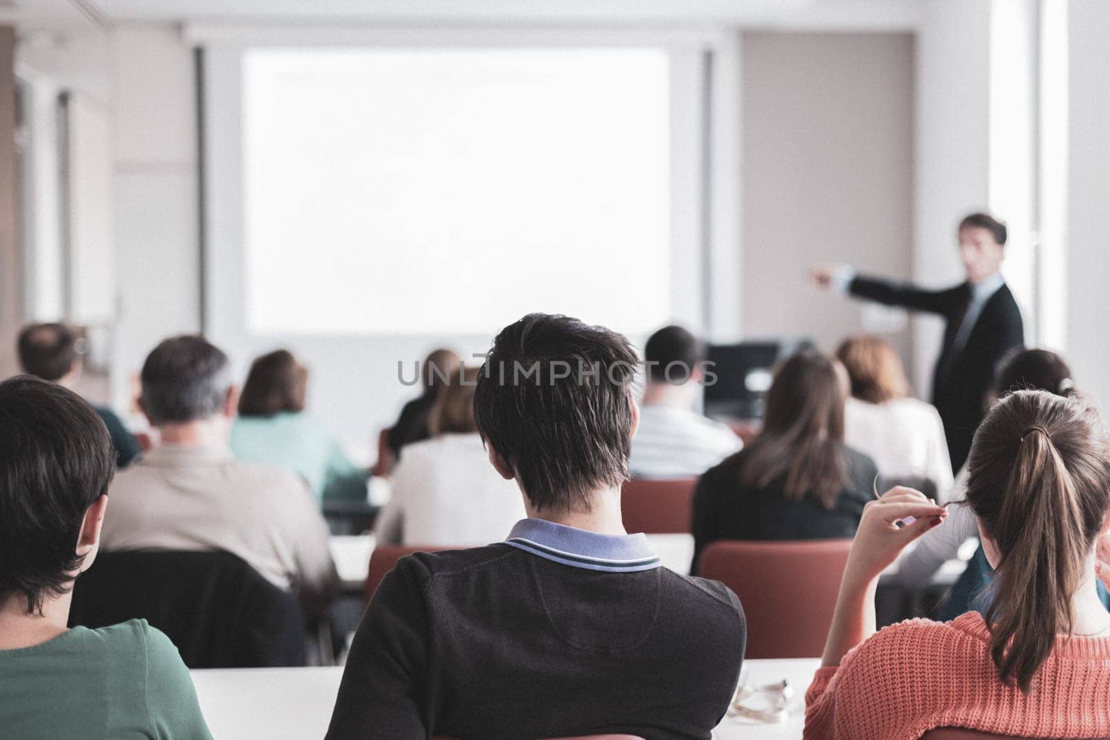 Speaker Giving a Talk at Business Meeting. Audience in the conference hall. Business and Entrepreneurship. Copy space on white board.