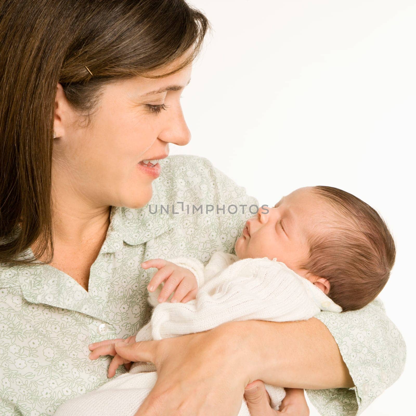 Mother holding baby smiling against white background.