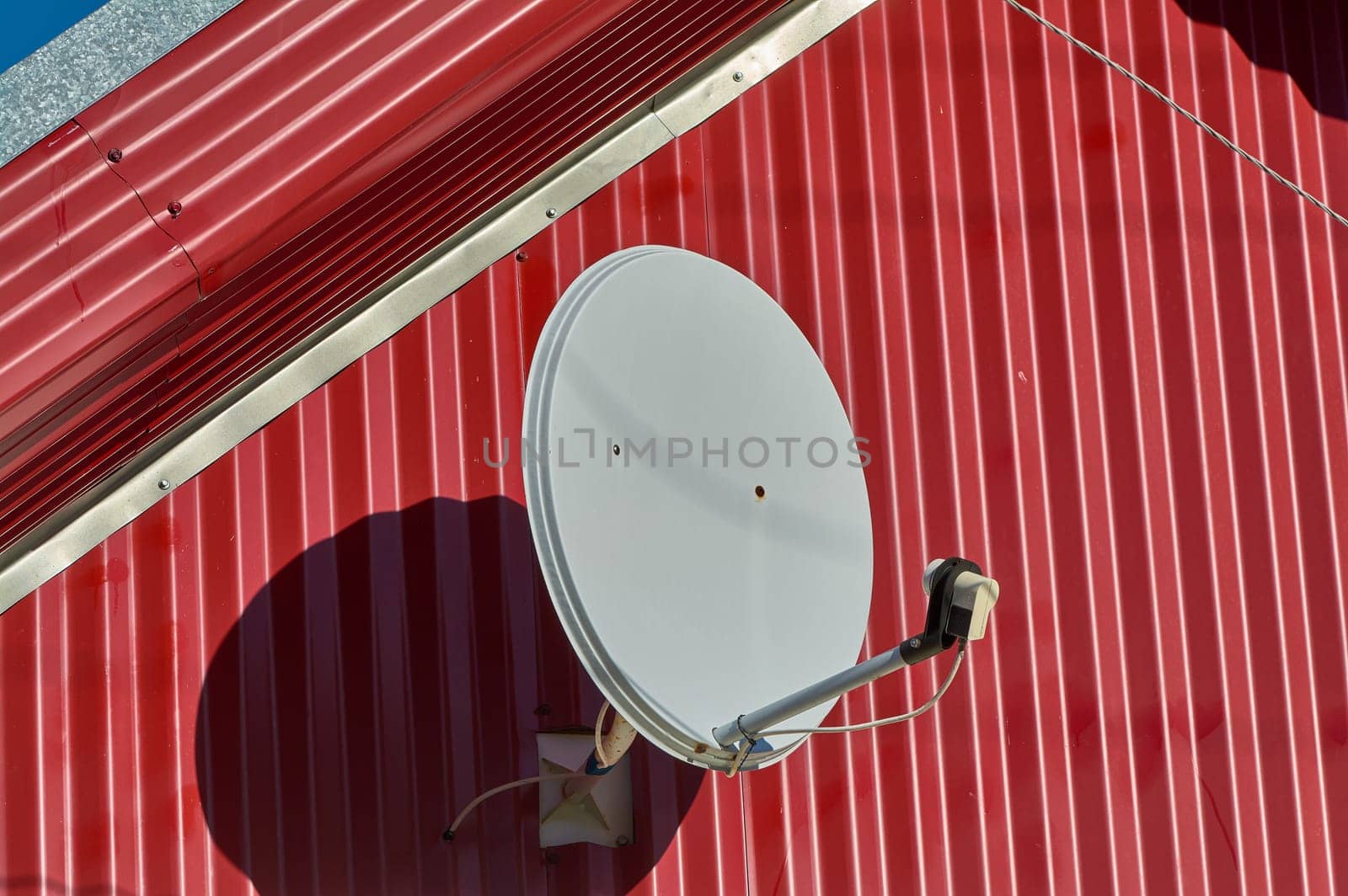 A satellite dish is hanging on the wall of the house. High quality photo