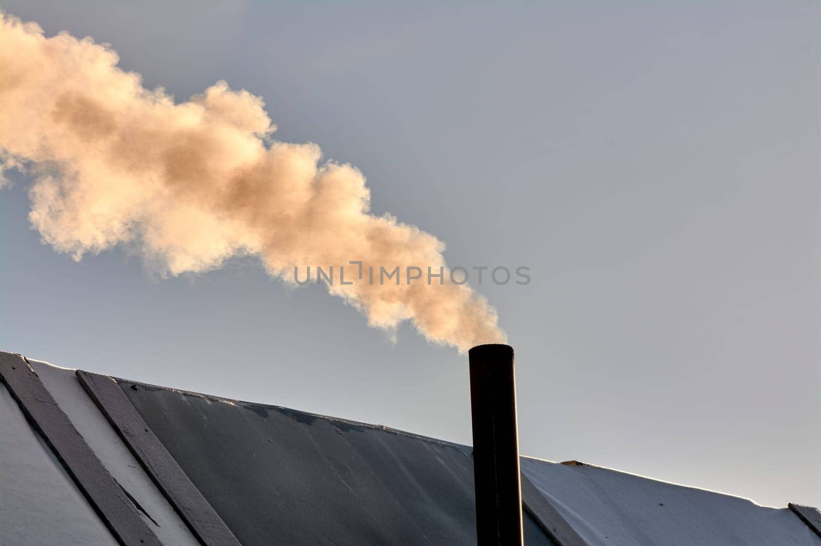 smoke is coming from the chimney of the bourgeoisie. the stove is being heated. High quality photo