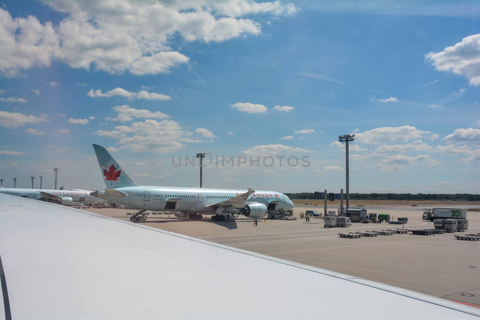 Frankfurt Airport Germany August 02, 2022 - View from the aircraft window onto a wing and a view of an Air Canada machine being loaded
