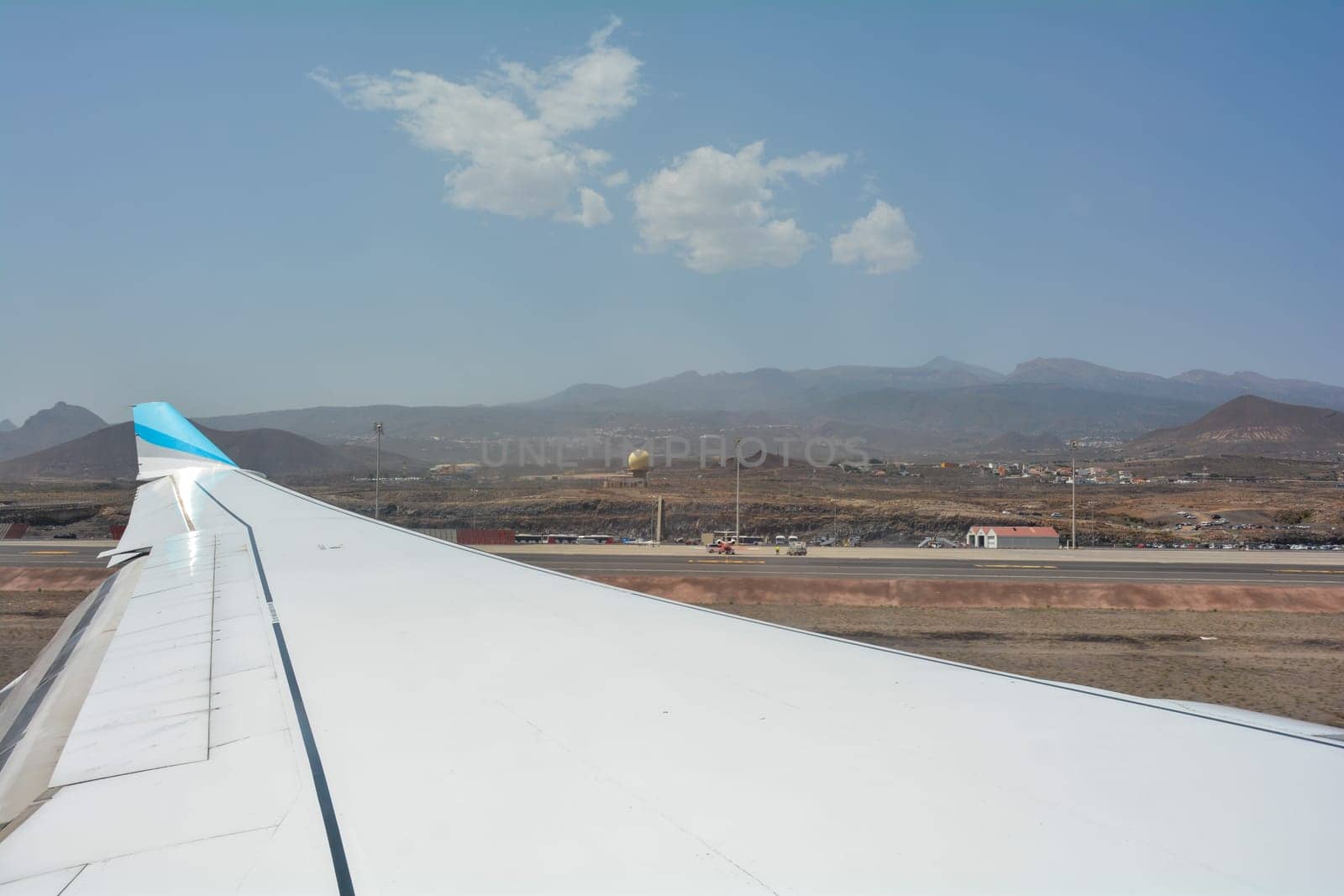 View from a murky airplane window on approach to Tenerife South Airport, Spain. Overlooking an airplane wing and countryside