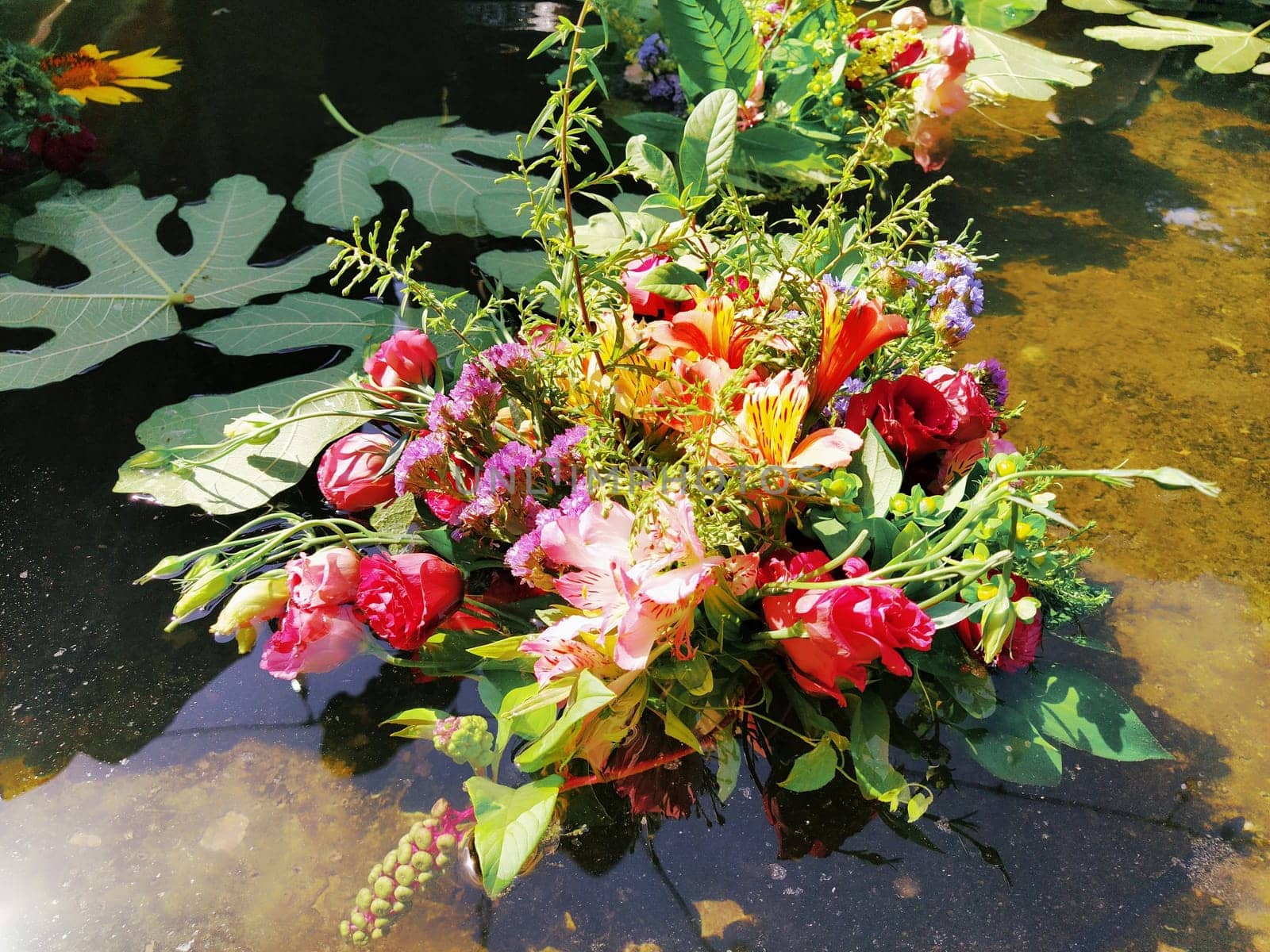 pink and red roses in a bouquet floating in the water of a fountain. Plucked buds as decoration for a summer holiday. Ivan Kupala, summer solstice. Harvest festival