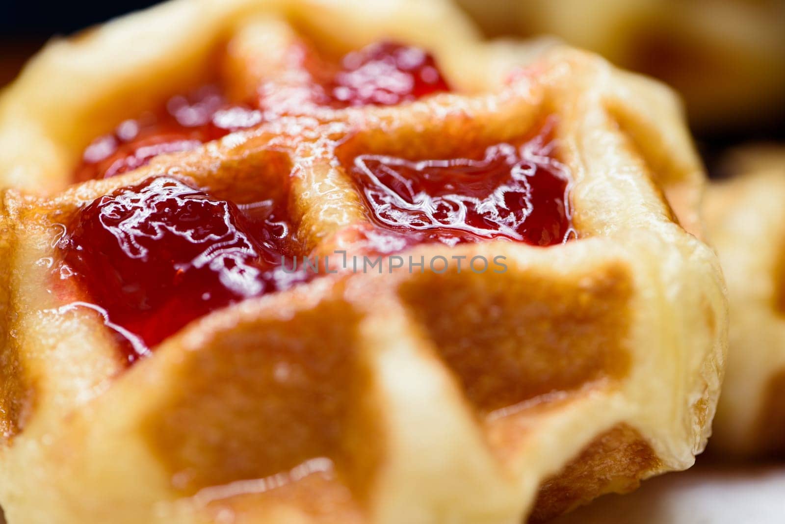 Close up of fresh waffles topped with delicious sweet strawberry jam and pineapple jam on top. Making homemade food or dessert at home