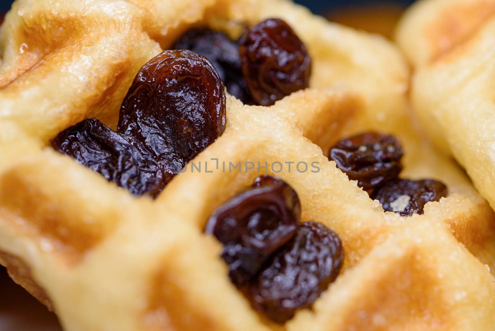 Close up of fresh waffles with dried raisins delicious sweet on top. Making homemade food or dessert at home