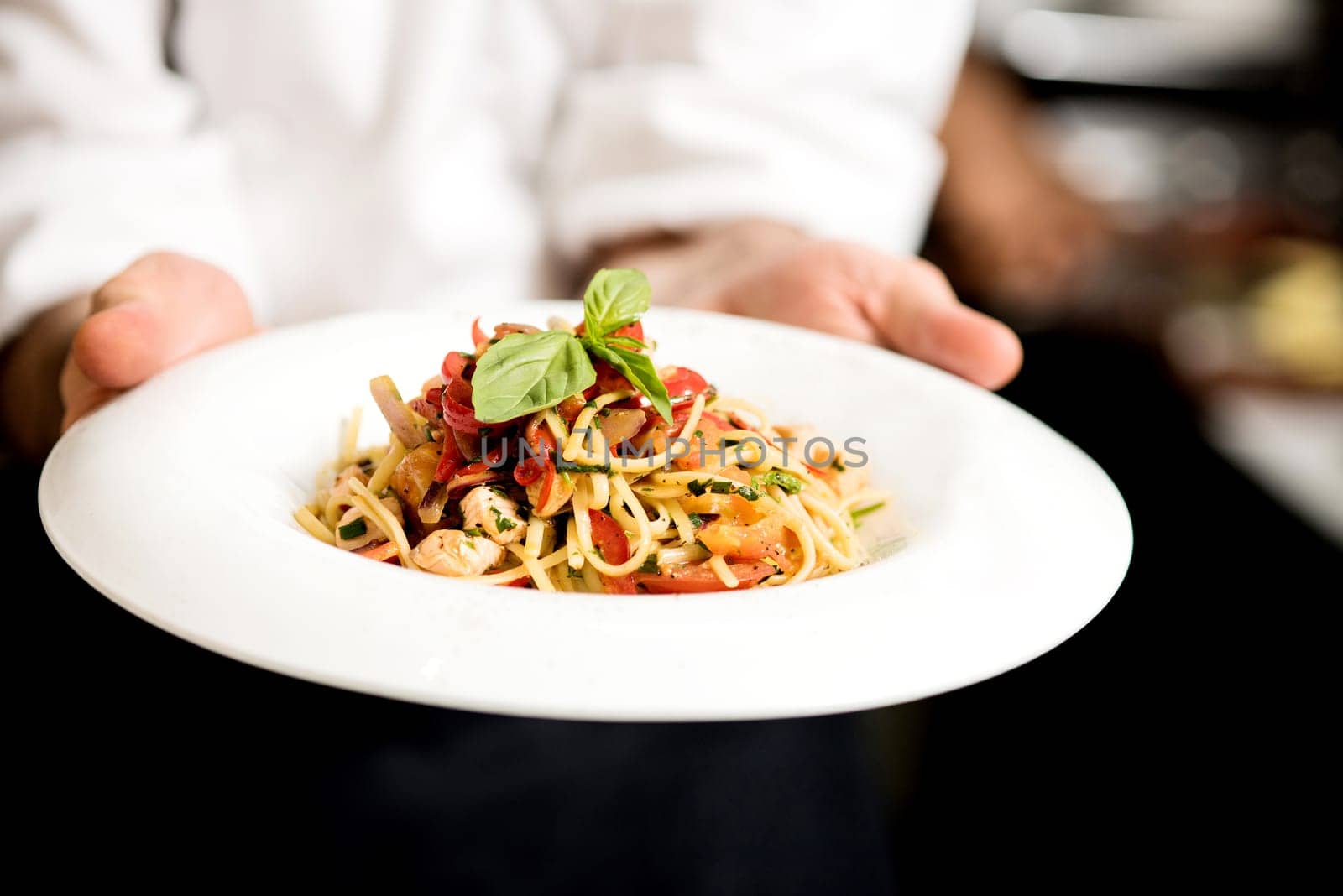 Chef hand holding tasty pasta dish