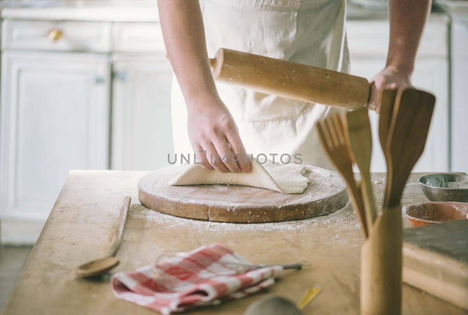 Man rolling and baking homemade dough in the kitchen. Closeup on baker's hands preparing loaf of bread. Cooking and food preparation at home.