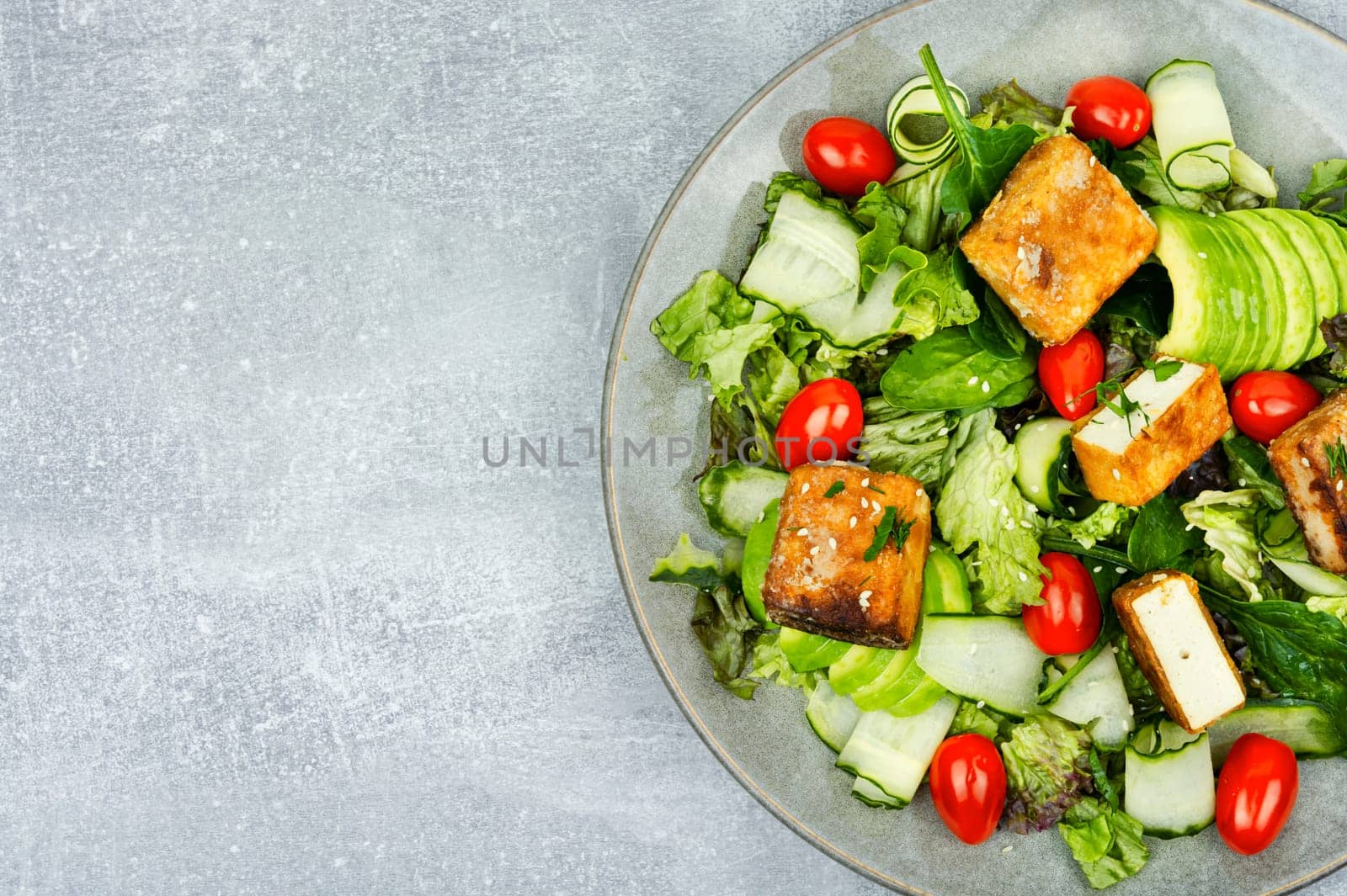 Tasty salad of greens, cucumber, avocado, tomatoes and grilled tofu soy cheese. Healthy Vegetarian Meals