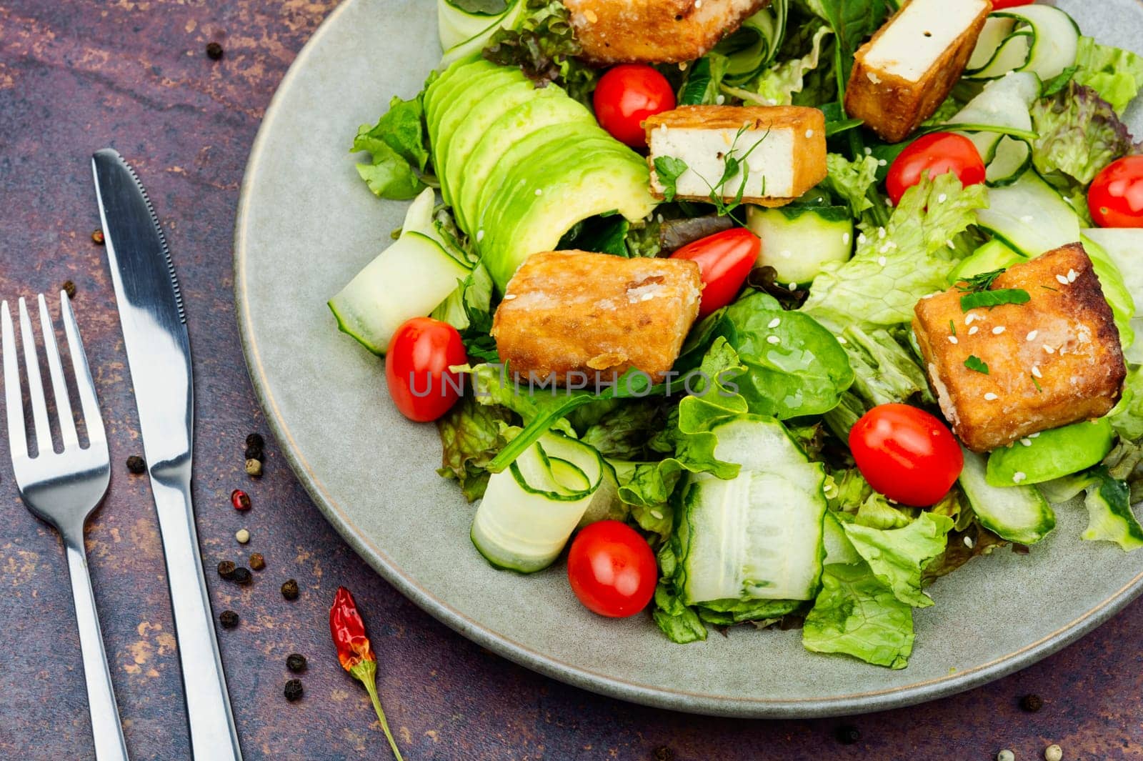 Tasty salad of greens, cucumber, avocado, tomatoes and grilled tofu soy cheese. Healthy Vegetarian Meals