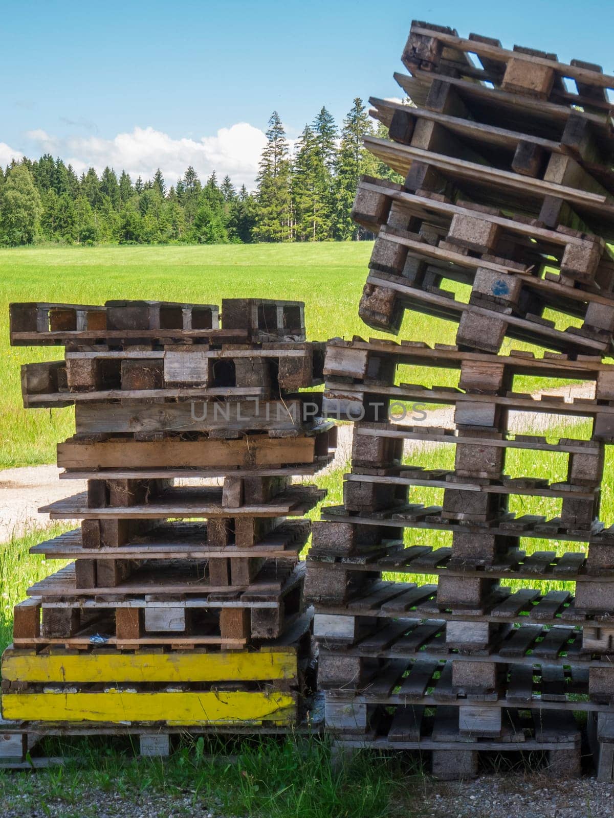 Landscape view with empty messy stacked pallets in foreground on green pasture in summer Bavaria.