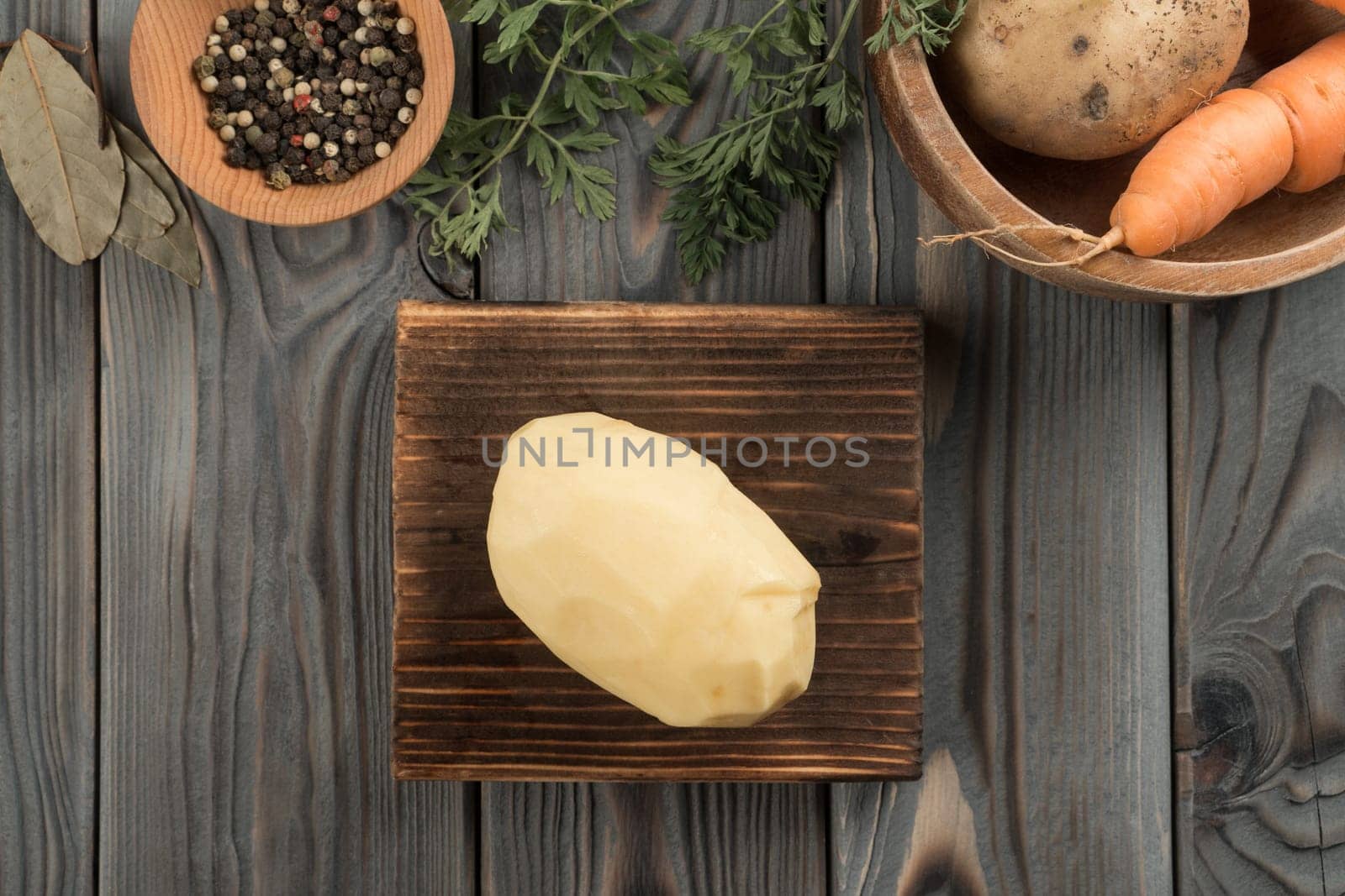 Raw yellow potato on kitchen wooden board. Fresh whole peeled potato, traditional cuisine. Flat lay view. Ripe vegetables and flavorings. Prepare ingredients for cooking. Healthy food.