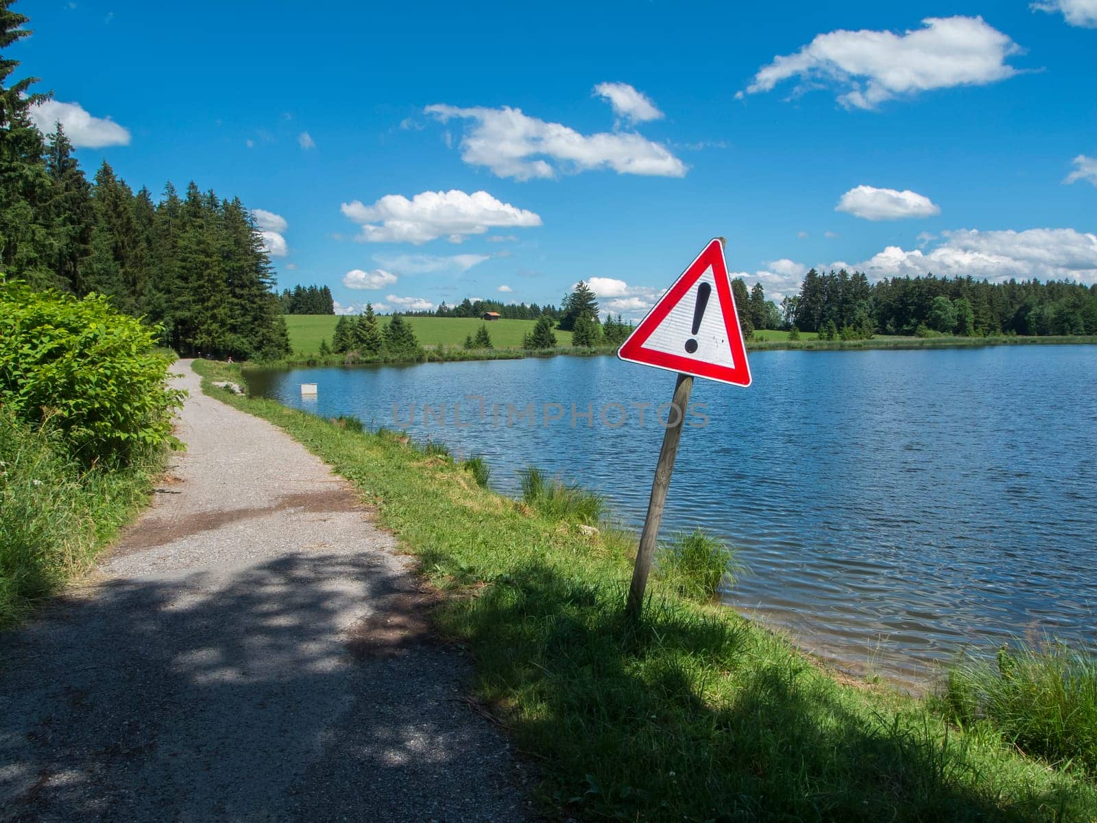 Road sign at the edge of the Pond Koegel in summer with a blue sky and small white clouds.