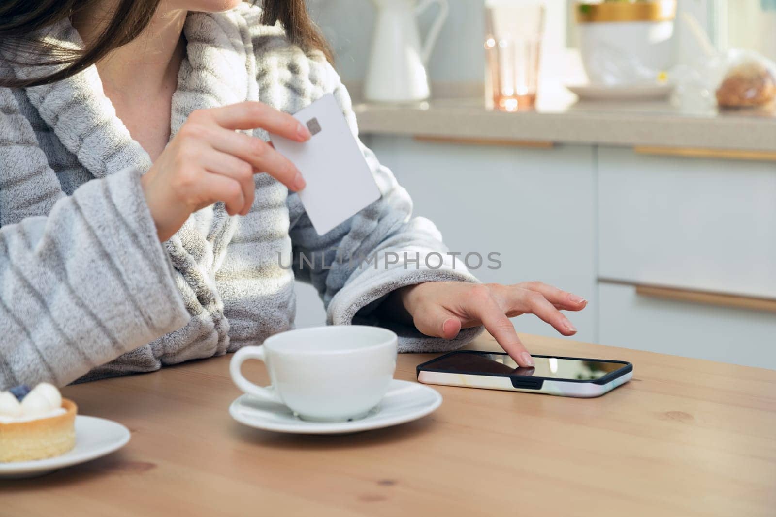 Woman using her debit card and smartphone to buy something online