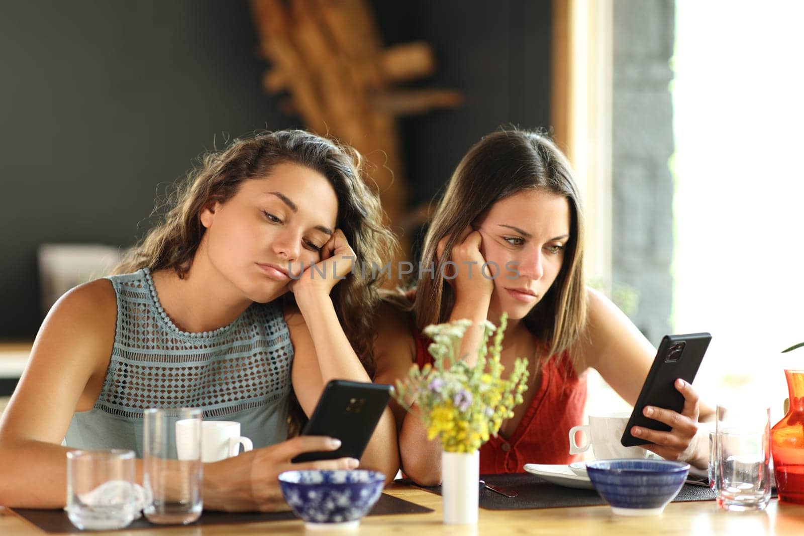 Bored friends checking smart phones in a restaurant