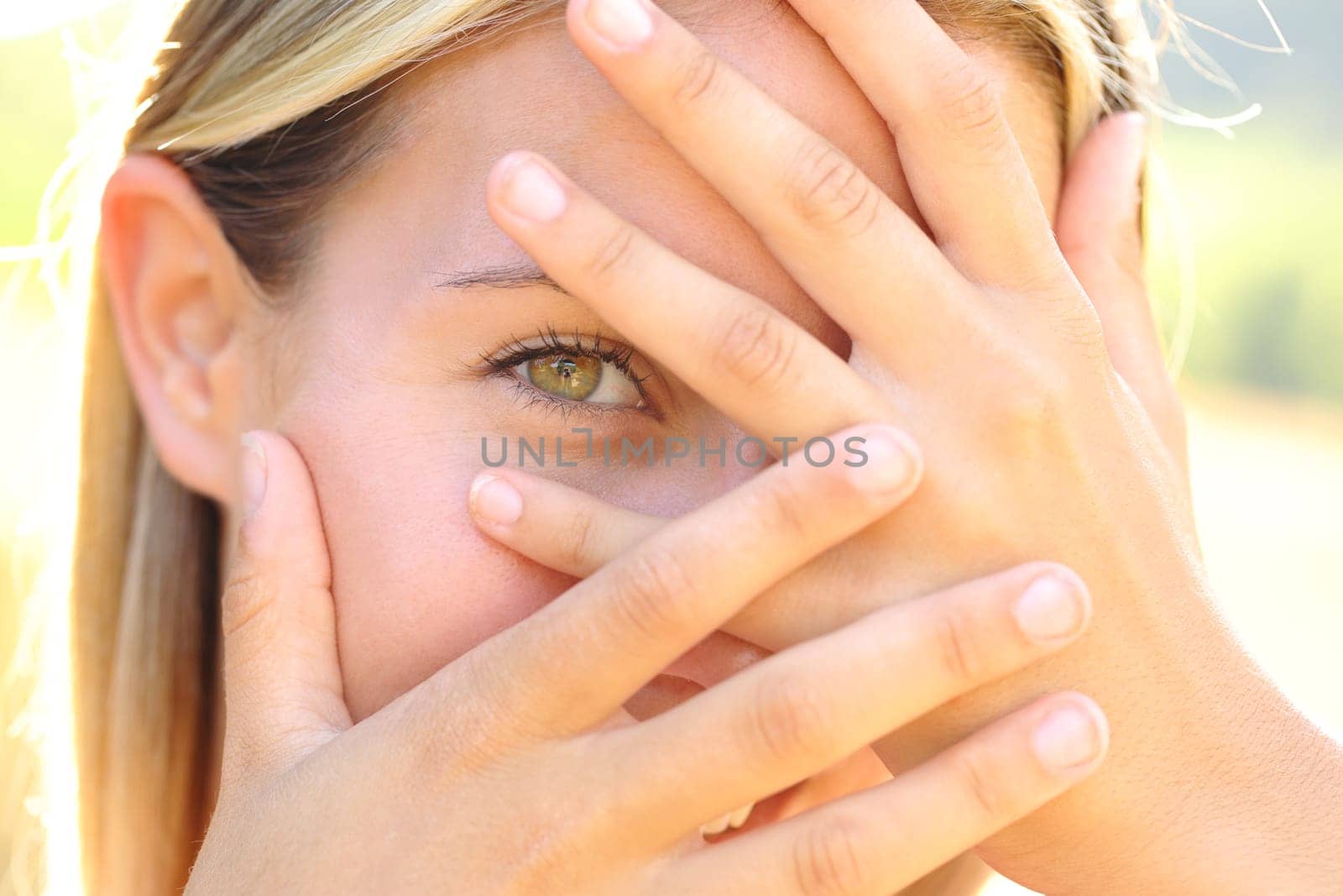 Front view portrait of a timid teen hiding behind her hands
