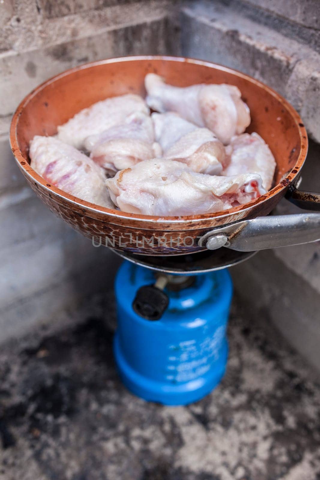 Spanish outdoor meal. Freshly chicken wings frying on a pan in camping gas stove