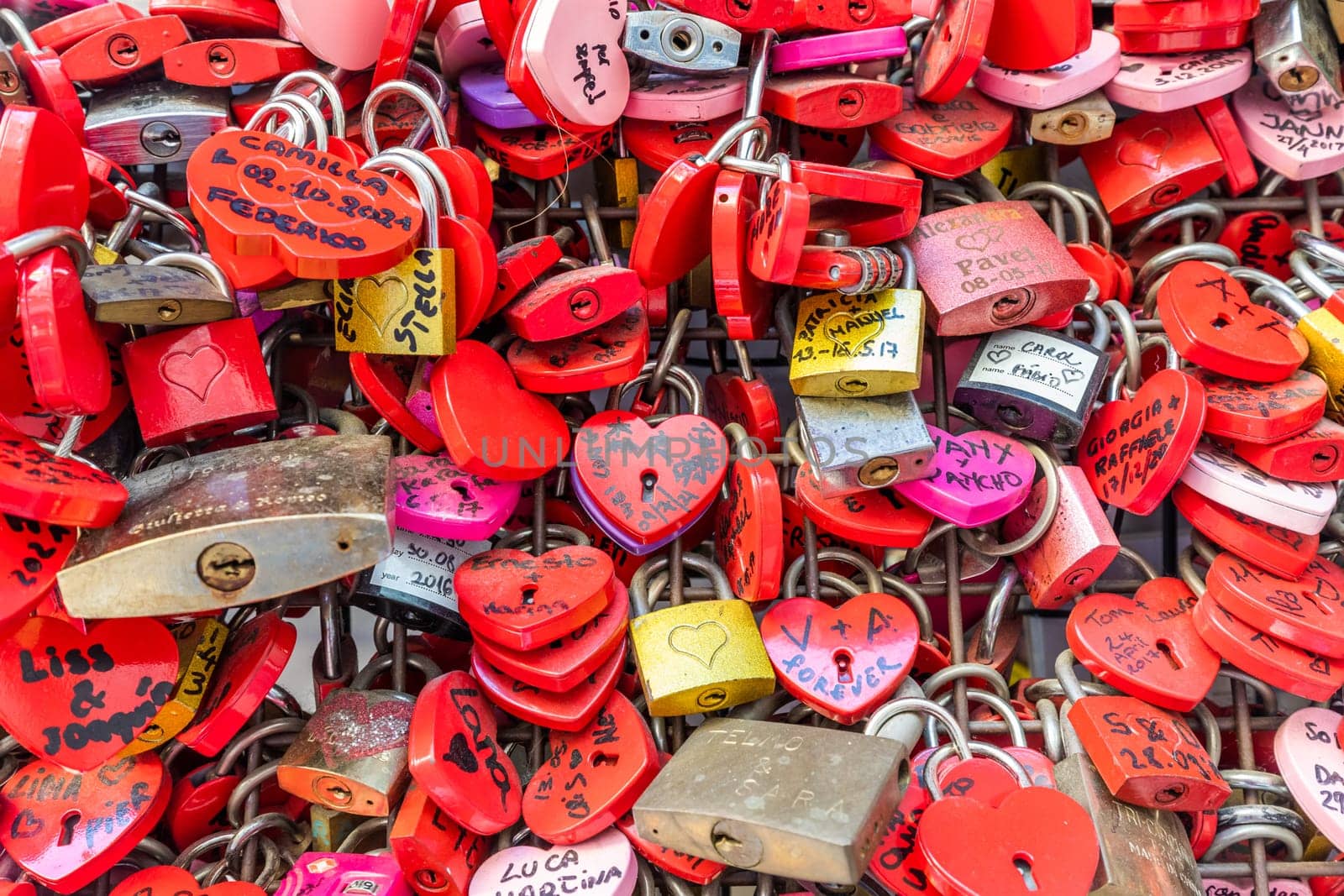 Verona, Italy - June 2022: background of heart-shaped locks on a wall, symbol of love forever