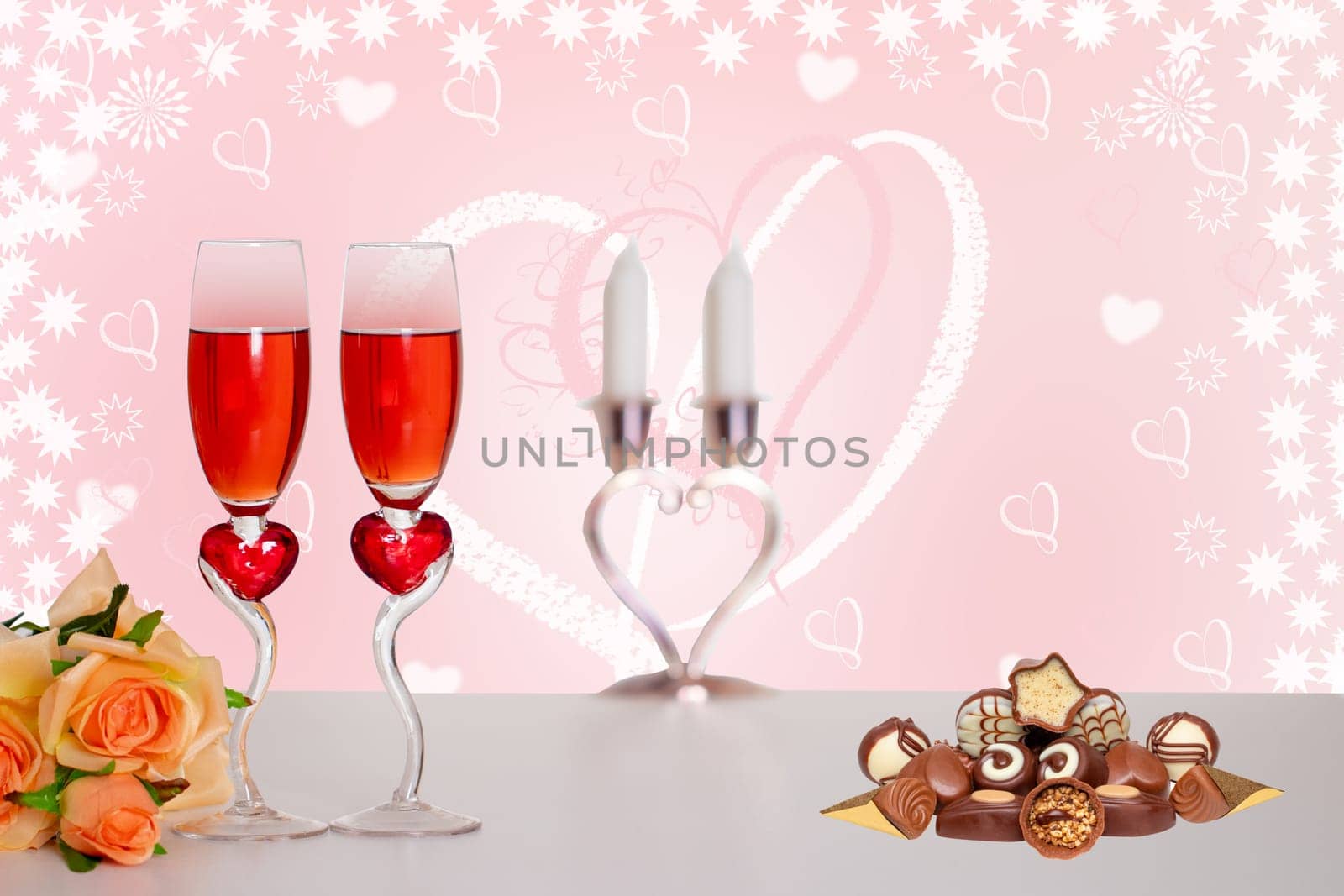 Happy Valentines or Mothers Day card. Two glasses of champagner, a bouquet flowers and a pile of chocolate candies on table over abstract heart background. Space.