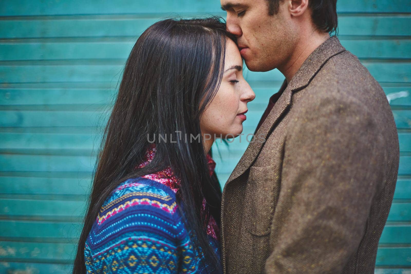 Amorous man kissing young woman on forehead