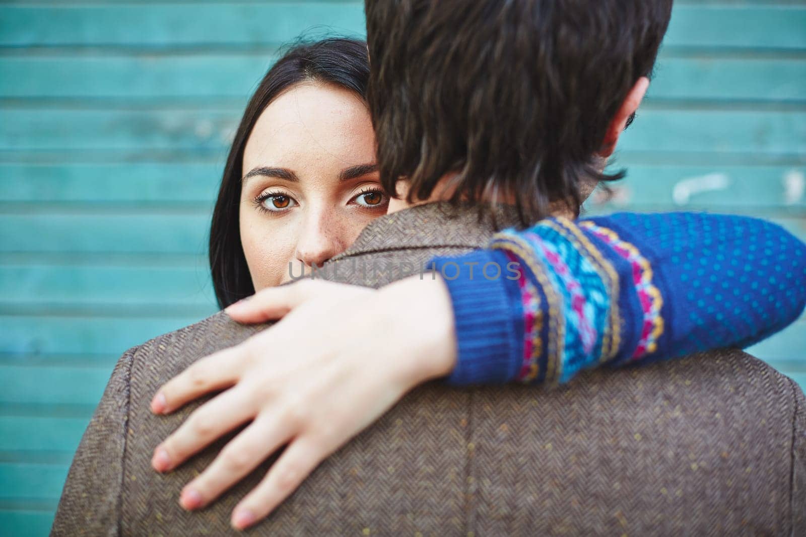 Young woman looking at camera out of man back while embracing him