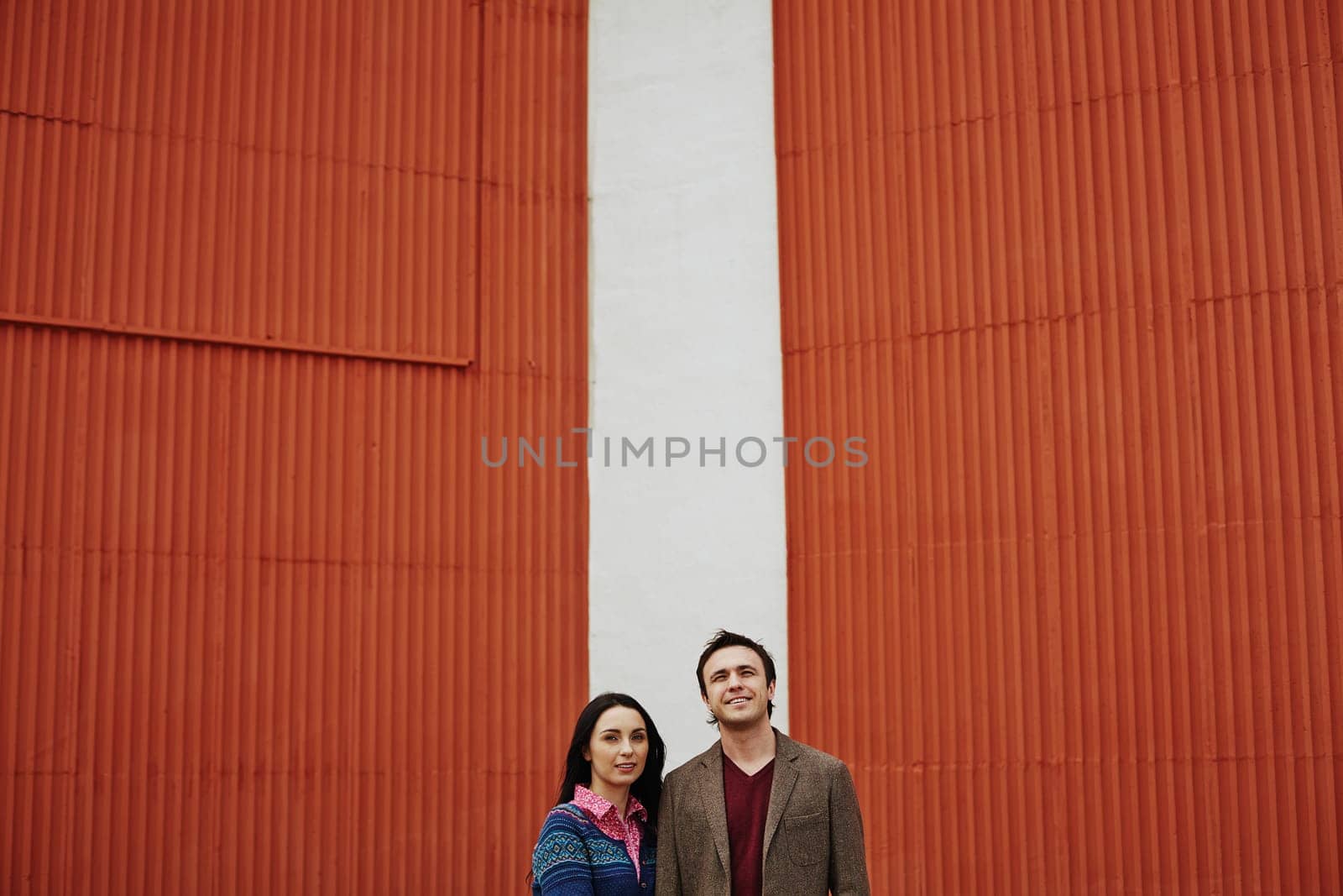 Young couple in casualwear standing by wall outside