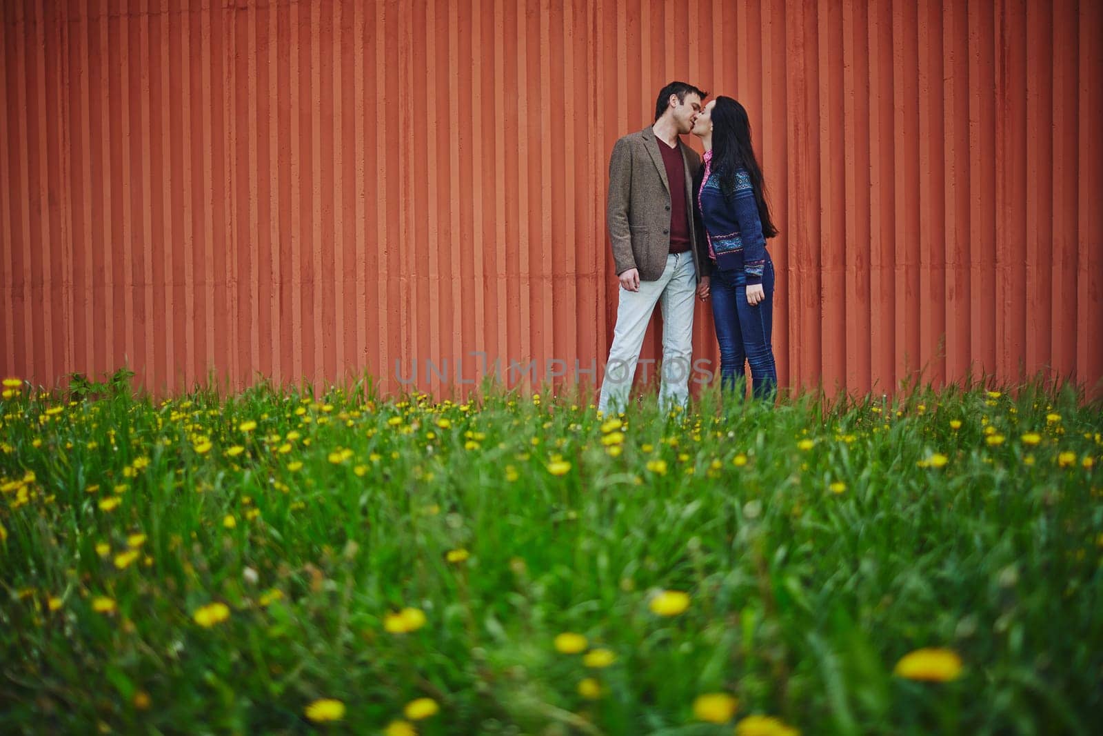 Amorous couple in casualwear kissing on green lawn