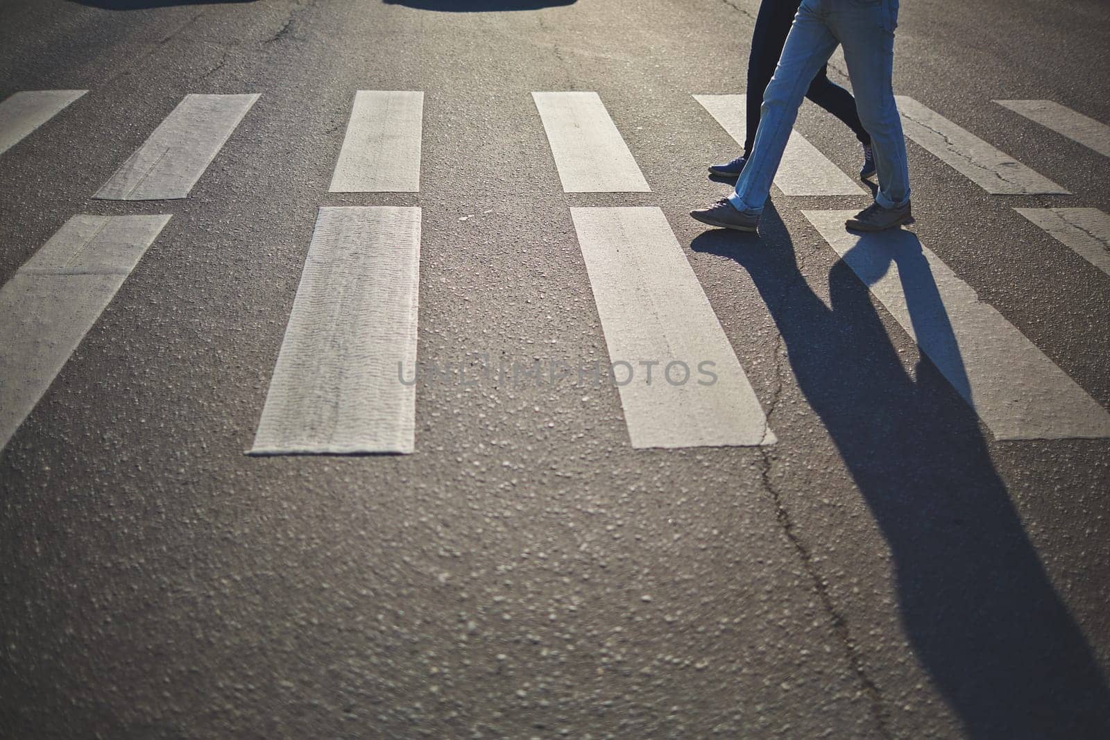Urban couple in jeans and sports shoes crossing road