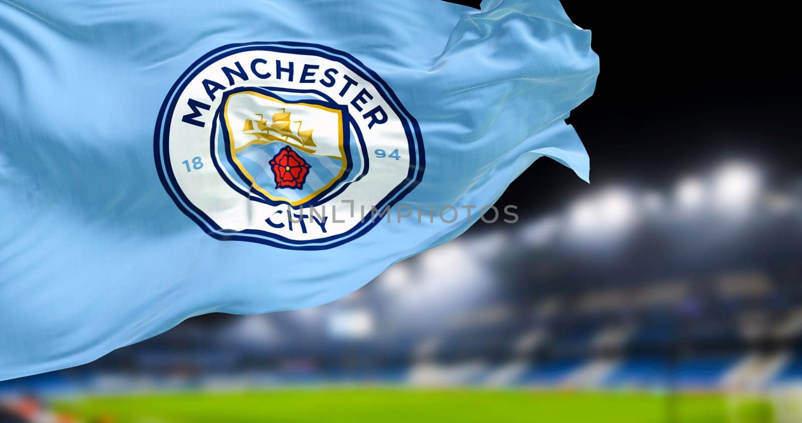 Manchester, UK, Nov 2022: Manchester City Football Club flag waving in the club stadium blurred in the background at night. Realistic 3d illustration. Illustrative editorial
