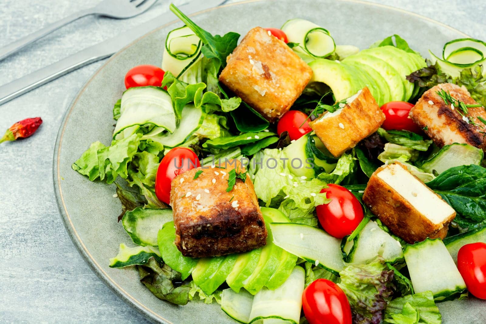 Delicious salad with lettuce, cucumber, avocado and roasted tofu soy cheese. Vegetarian cuisine