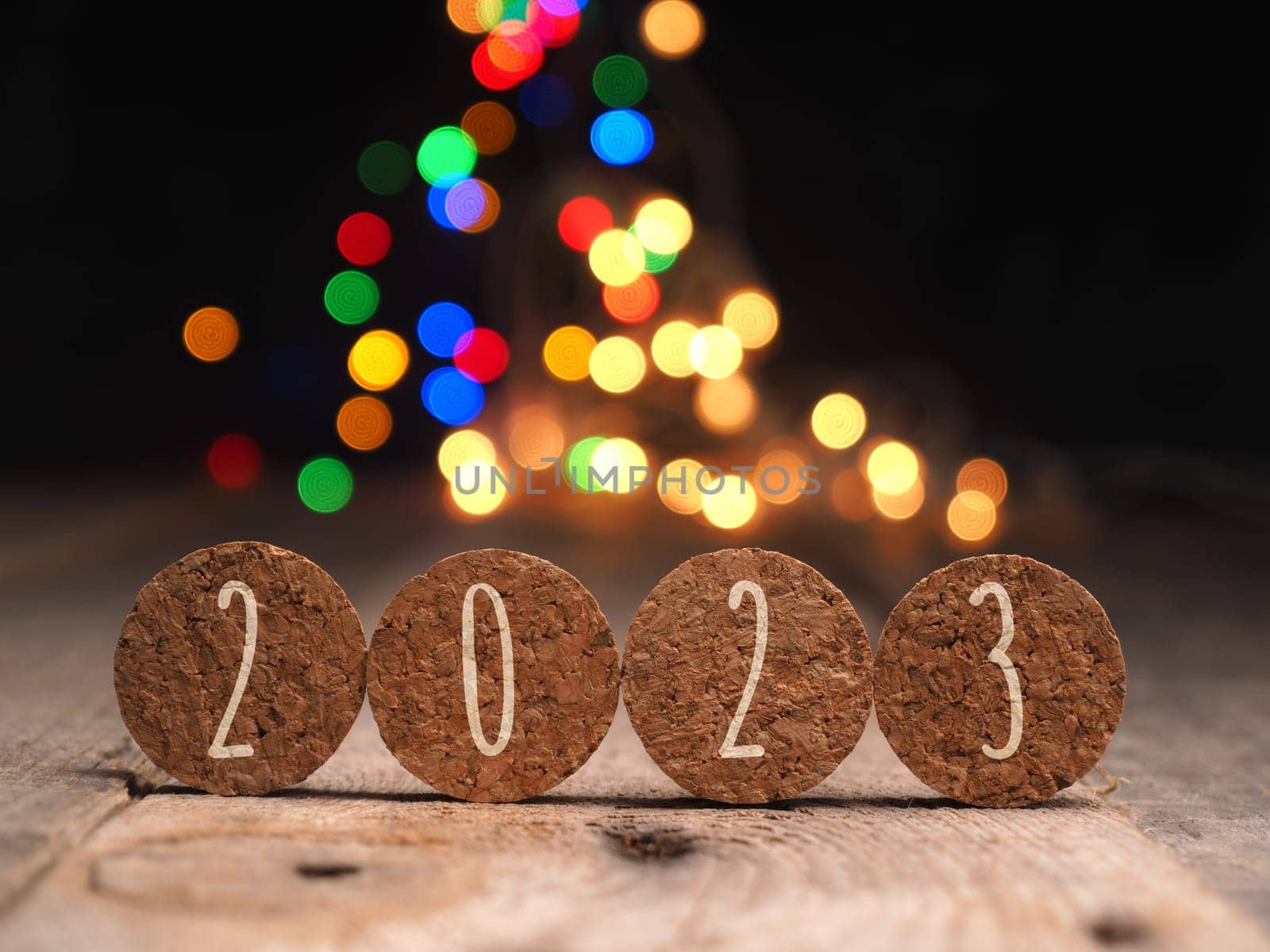 Bottle cork with the inscription 2023 on colorful Christmas lights background