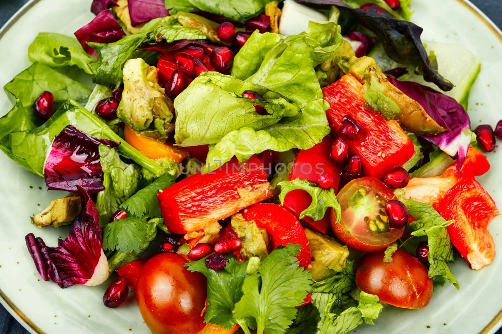 Vitamin salad with greens, pepper, red lettuce and cucumber, decorated with pomegranate.